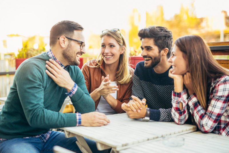 group of people meeting outside talking at table